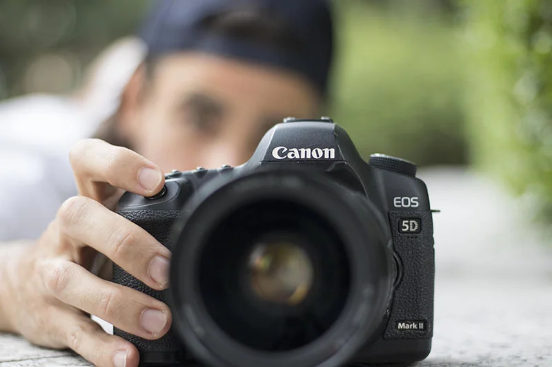 Homem enquadrando imagem com câmera DSLR