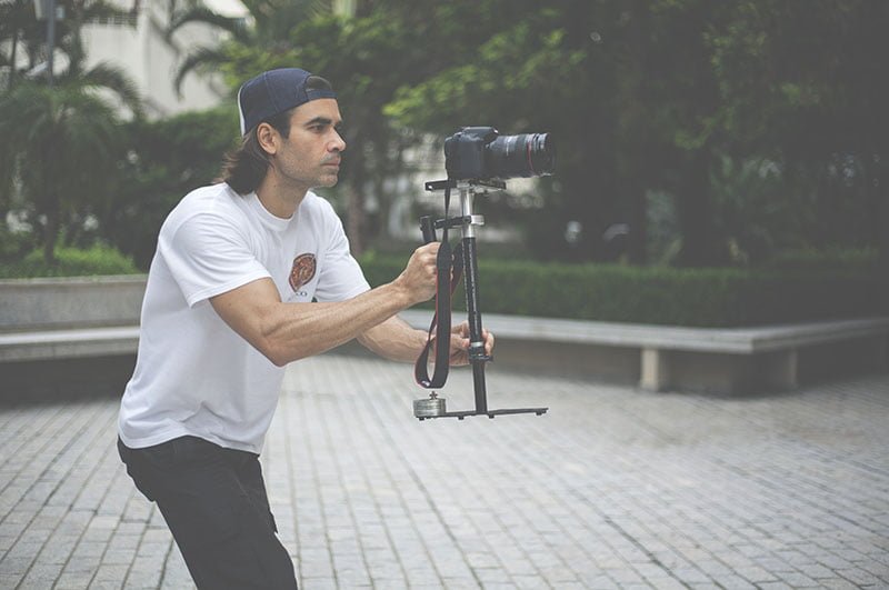 Homem segurando câmera DSLR com estabilizador manual