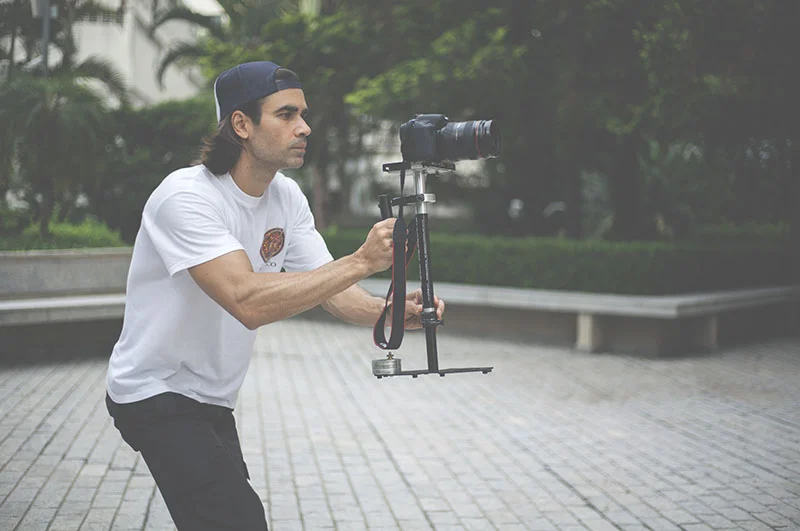 Homem segurando câmera DSLR com estabilizador manual