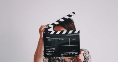 Mulher segurando claquete de cinema em frente ao rosto