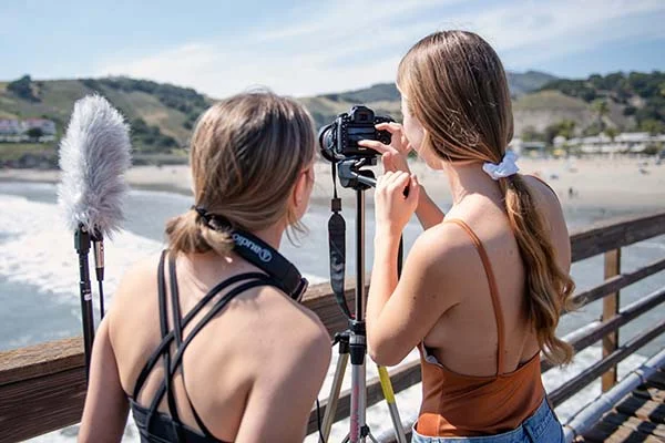 estudantes de cinema e audiovisual filmando durante o dia em cima de um pier